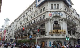 In front of a large building, there are people on the street and an old-style storefront across at Jinjiang Inn Select (Shanghai Nanjing Road Pedestrian Street)
