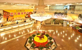 a large , well - lit hotel lobby with a red carpeted floor and a chandelier hanging from the ceiling at Rome Hotel