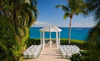 A wedding ceremony is arranged on the beach, featuring chairs and gazebos that offer a picturesque view of the ocean at The Westin Beach Resort & Spa at The Westin Beach Resort & Spa at Frenchman’s Reef