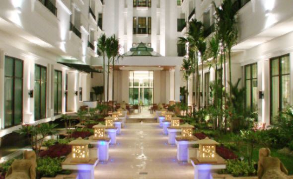 a large hotel lobby with a staircase leading to the second floor , surrounded by potted plants at Tara Angkor Hotel