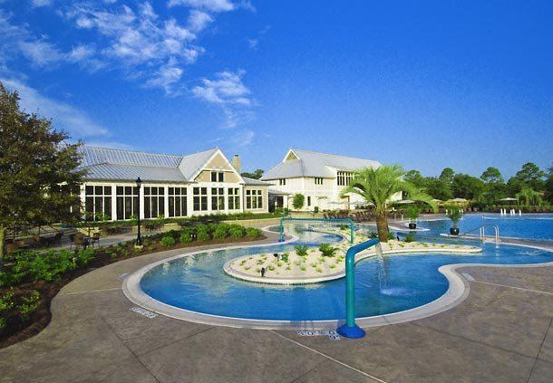 a large swimming pool with a fountain and a building in the background , surrounded by grass and trees at The Grand Hotel Golf Resort & Spa, Autograph Collection