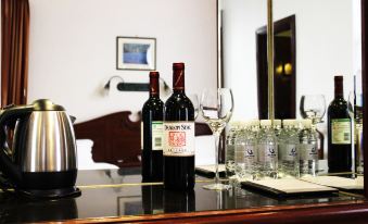 There are two wine bottles sitting next to a bottle and glasses on the table in an empty room at Pacific Hotel