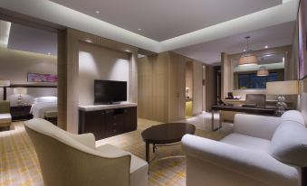 a modern living room with a large flat - screen tv mounted on the wall , a couch , and a dining table at Sheraton Qinhuangdao Beidaihe  Hotel