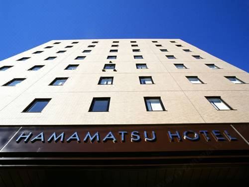 a modern hotel building with a large sign above the entrance , under a clear blue sky at Hamamatsu Hotel
