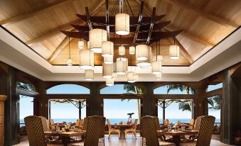 a restaurant with wooden tables and chairs , large windows , and a view of the ocean at Four Seasons Resort Lana'i