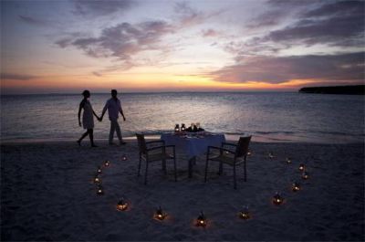 a romantic dinner on the beach , with candles and flowers arranged for a romantic setting at Vilamendhoo Island Resort & Spa
