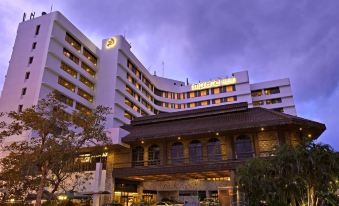a large hotel building with a parking lot in front of it , surrounded by trees at Impiana Hotel Ipoh
