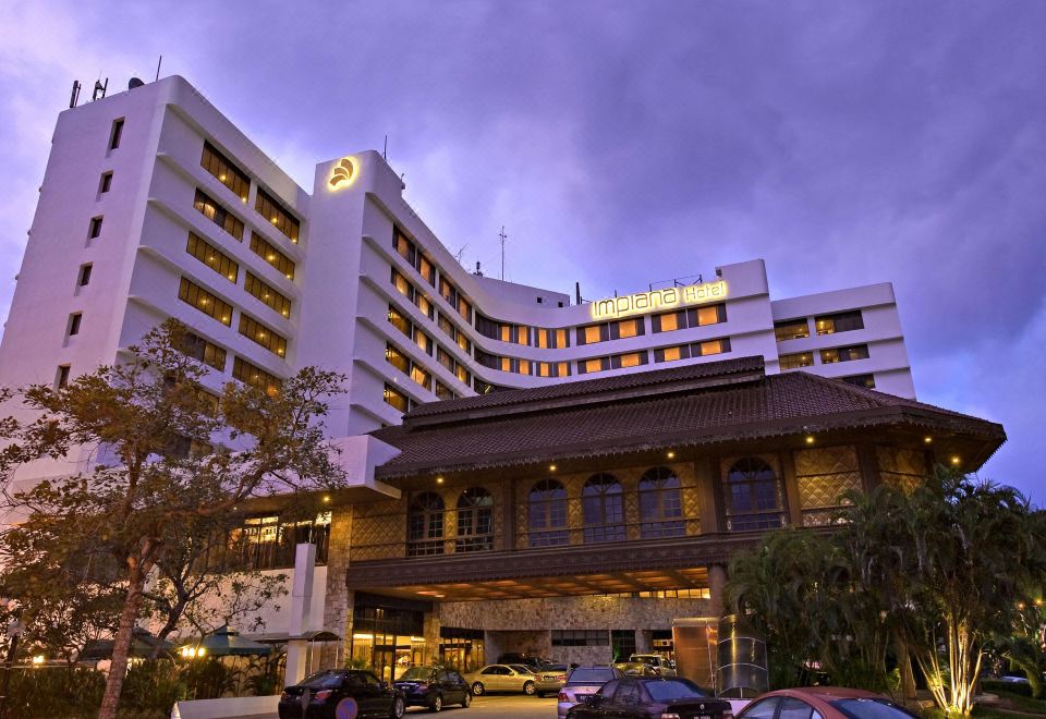 a large hotel building with a large parking lot in front of it , illuminated at night at Impiana Hotel Ipoh