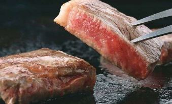 a large piece of meat , possibly a steak , being cooked on a grill in a frying pan at Kichijoji Tokyu Rei Hotel