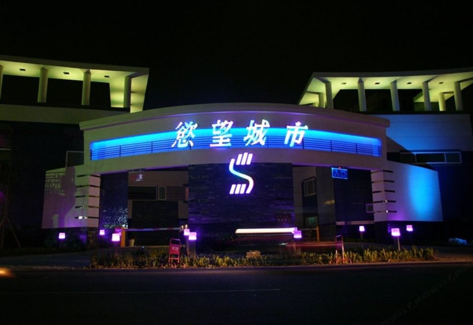 The hotel building is illuminated at night, surrounded by vibrant lights at Sex and the City Motel