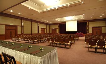 a large conference room with rows of chairs arranged in a semicircle , and a projector screen mounted on the wall at Berjaya Tioman Resort