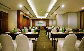 "a conference room with several tables and chairs , a projector screen on the wall , and the word "" aston "" is displayed on the screen" at ASTON Pluit Hotel & Residence